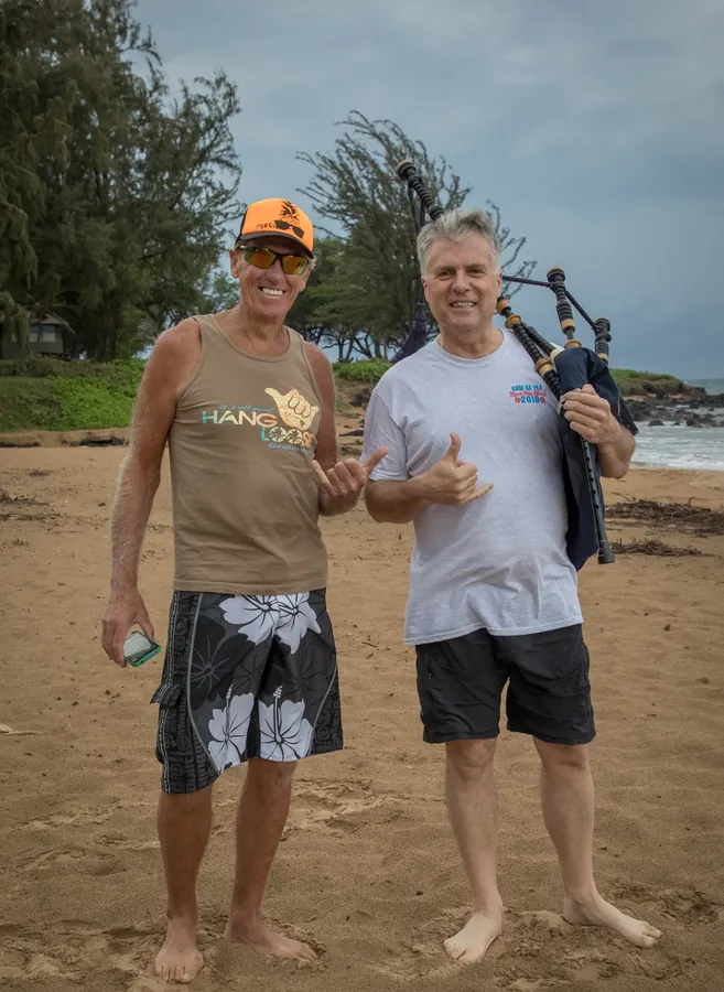 Two band members smiling on the beach, one with pipes