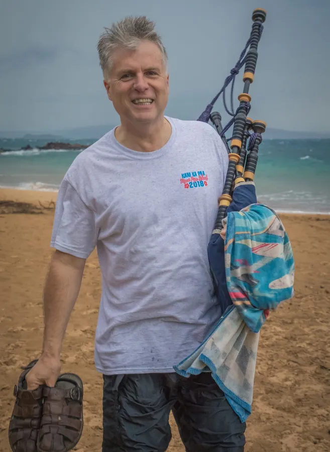 A smiling piper on the beach holding his pipes