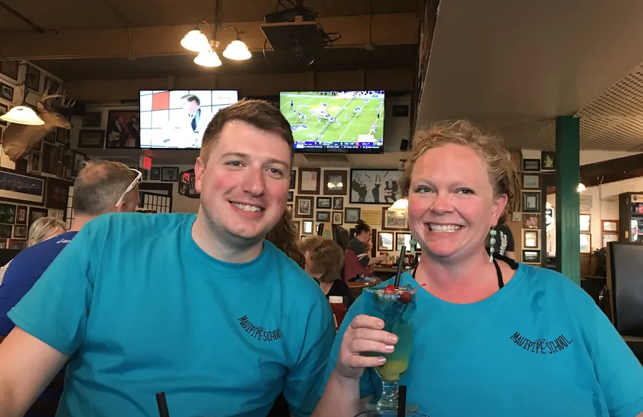 Two friends in school shirts smiling with drinks